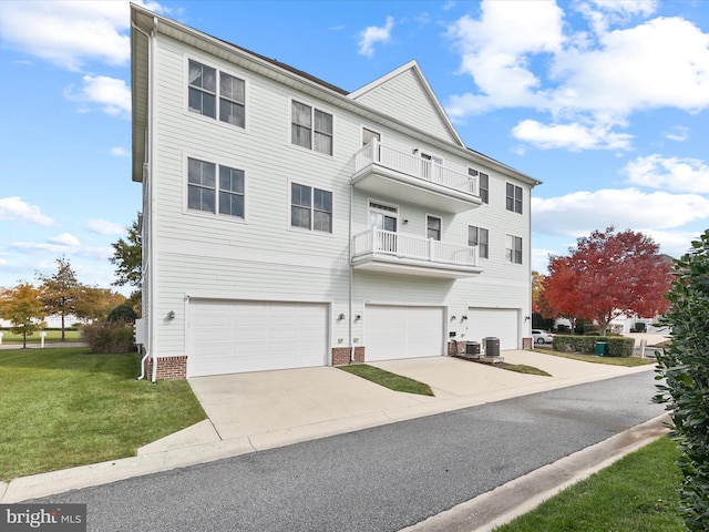 multi unit property with cooling unit, a front lawn, a garage, and a balcony