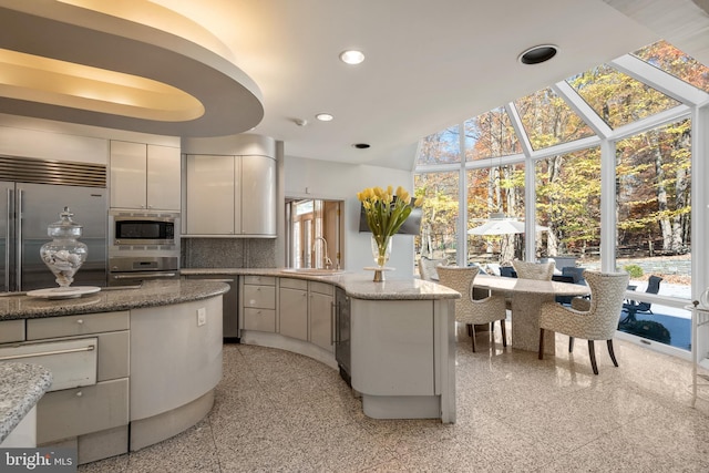 kitchen featuring backsplash, built in appliances, white cabinetry, and sink