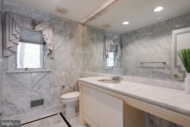 bathroom with vanity, toilet, and tile walls