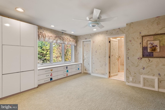 interior space with light colored carpet, ensuite bath, and ceiling fan