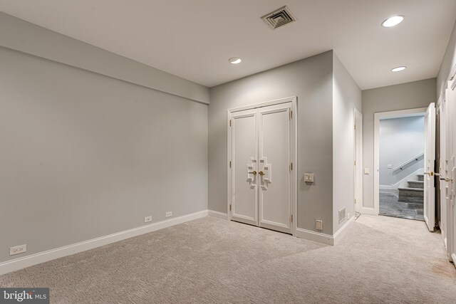 unfurnished bedroom featuring light colored carpet and a closet