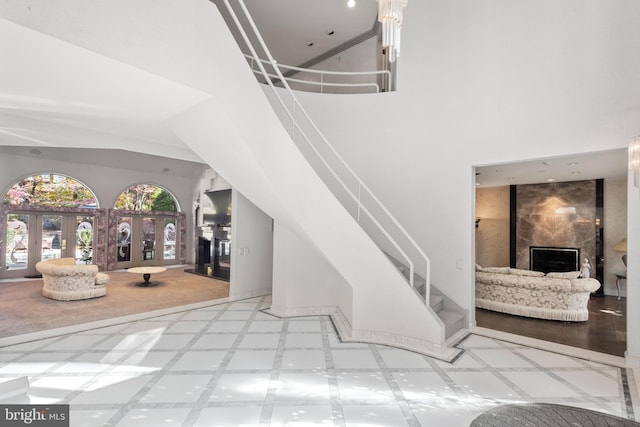 stairway featuring a fireplace, french doors, a towering ceiling, and tile patterned flooring