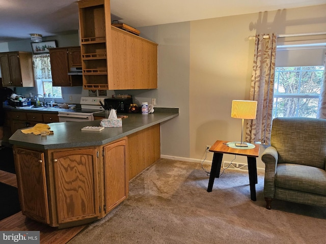 kitchen featuring sink, white range with electric stovetop, kitchen peninsula, and light colored carpet