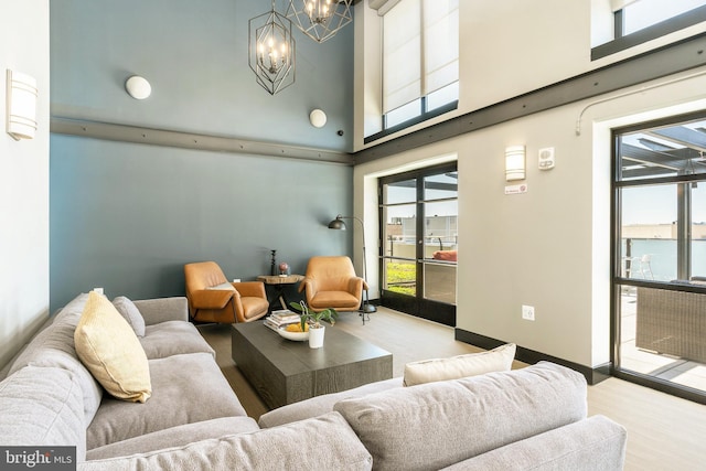 living room with light hardwood / wood-style flooring, a high ceiling, and an inviting chandelier