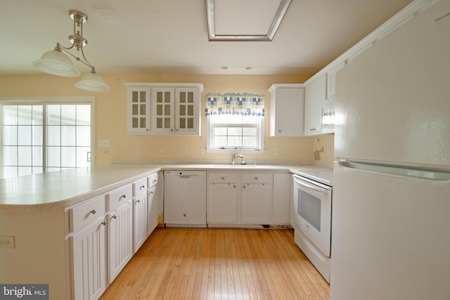 kitchen featuring white appliances, kitchen peninsula, hanging light fixtures, white cabinetry, and light hardwood / wood-style flooring