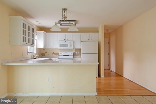 kitchen featuring white appliances, white cabinetry, light hardwood / wood-style flooring, and kitchen peninsula