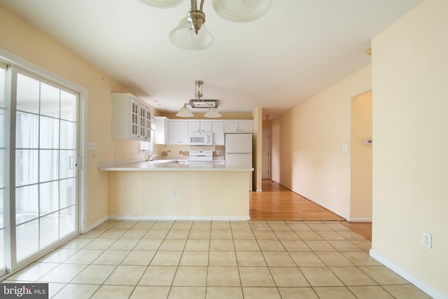 kitchen with light hardwood / wood-style flooring, hanging light fixtures, kitchen peninsula, white cabinets, and white appliances