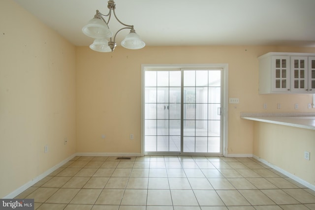 unfurnished dining area featuring a chandelier and light tile patterned flooring