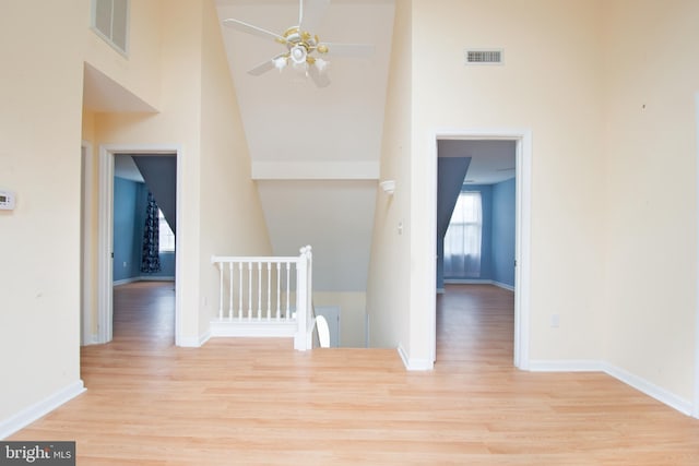 hall featuring light hardwood / wood-style floors and a towering ceiling