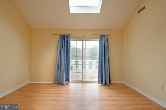 unfurnished room featuring light hardwood / wood-style floors and vaulted ceiling with skylight