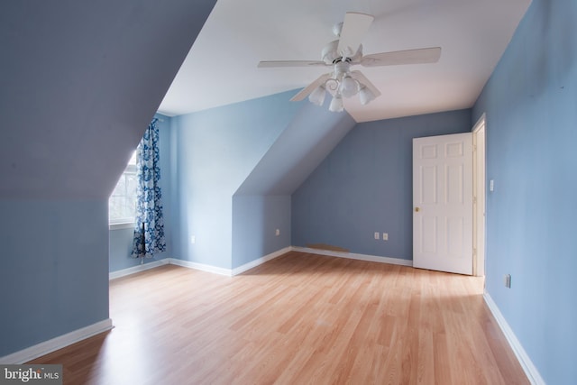 additional living space with light hardwood / wood-style floors, vaulted ceiling, and ceiling fan