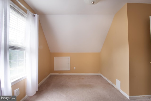 bonus room with a wealth of natural light, vaulted ceiling, and light carpet