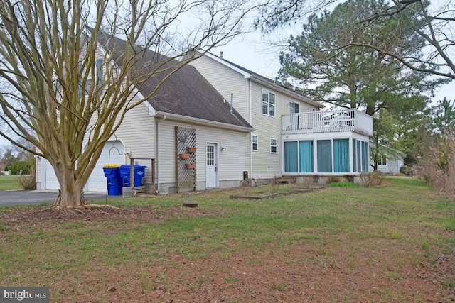 rear view of property featuring a garage, a lawn, and a balcony