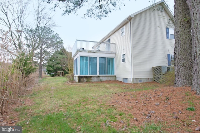 rear view of property featuring a balcony and a lawn