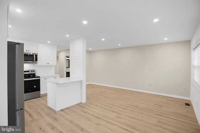 kitchen featuring appliances with stainless steel finishes, white cabinets, and light wood-type flooring