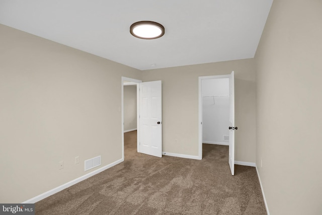 unfurnished bedroom featuring a spacious closet, a closet, and carpet floors