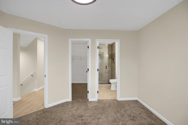 unfurnished bedroom with a spacious closet, connected bathroom, carpet floors, and a closet