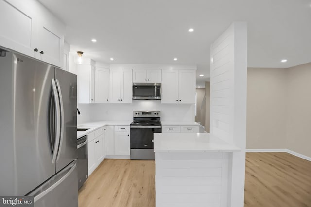 kitchen with sink, light wood-type flooring, kitchen peninsula, white cabinetry, and stainless steel appliances