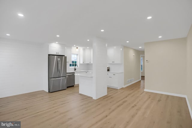 kitchen featuring sink, a kitchen island, white cabinetry, light hardwood / wood-style floors, and stainless steel appliances