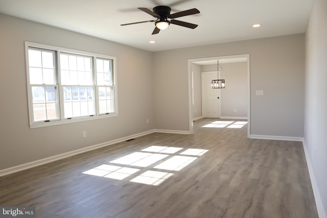 spare room featuring hardwood / wood-style flooring and ceiling fan with notable chandelier