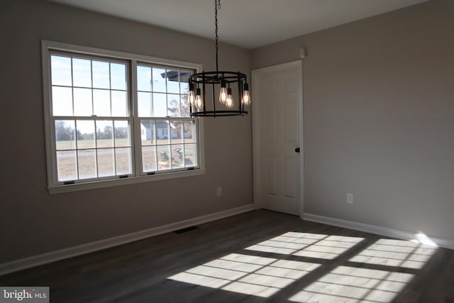 unfurnished dining area with dark wood-type flooring and a chandelier