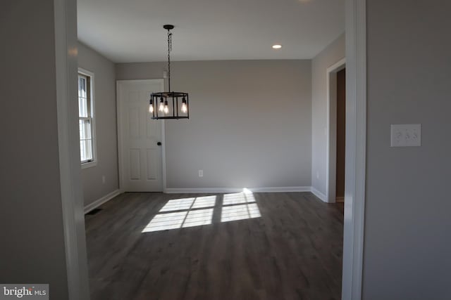 unfurnished dining area with dark hardwood / wood-style floors and a chandelier