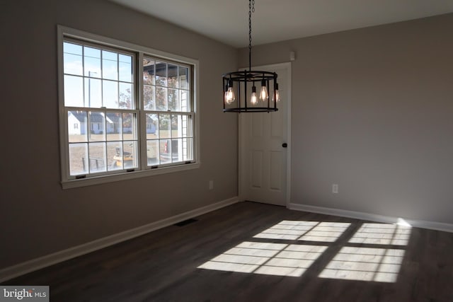 unfurnished dining area featuring dark hardwood / wood-style flooring, a notable chandelier, and a healthy amount of sunlight