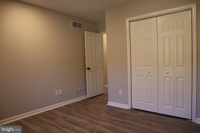 unfurnished bedroom with dark hardwood / wood-style floors and a closet