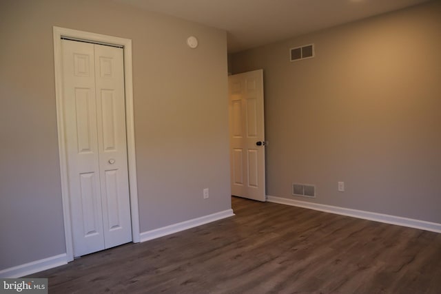 unfurnished bedroom featuring a closet and dark hardwood / wood-style flooring