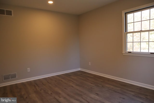 spare room featuring dark hardwood / wood-style flooring and plenty of natural light