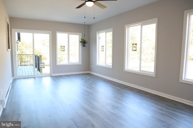 empty room featuring ceiling fan, baseboard heating, and dark hardwood / wood-style flooring