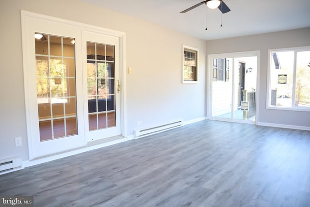 spare room featuring a baseboard heating unit, ceiling fan, and hardwood / wood-style flooring