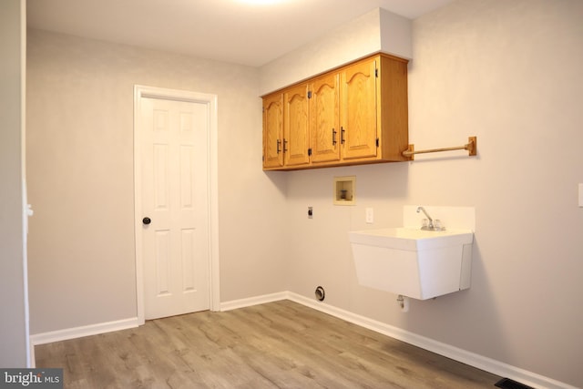 clothes washing area with hookup for an electric dryer, hookup for a washing machine, cabinets, light hardwood / wood-style flooring, and sink