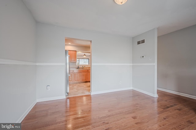 spare room with sink and light hardwood / wood-style flooring