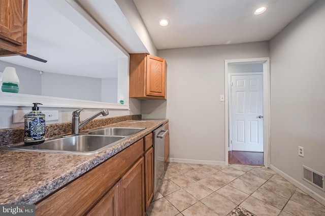 kitchen with stainless steel dishwasher, sink, and light tile patterned floors