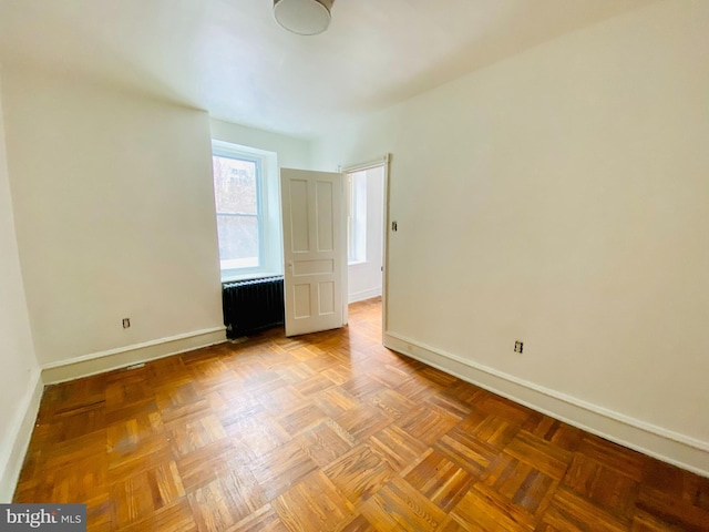 empty room with light parquet flooring and radiator