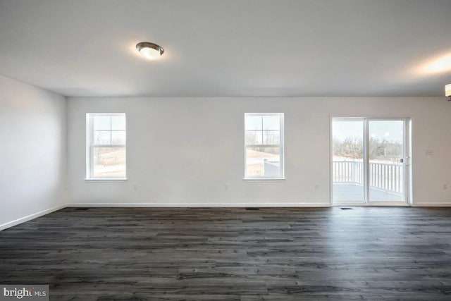 spare room with baseboards and dark wood-style flooring