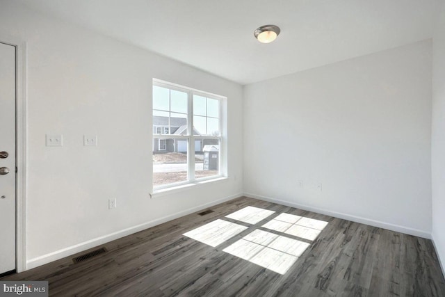 spare room featuring visible vents, baseboards, and wood finished floors