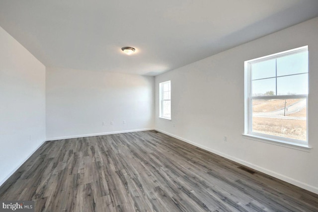 unfurnished room featuring visible vents, baseboards, and wood finished floors