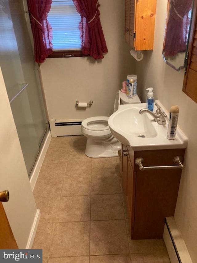 bathroom featuring walk in shower, vanity, a baseboard heating unit, tile patterned floors, and toilet