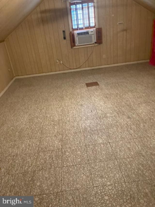 bonus room with wood walls, cooling unit, and vaulted ceiling