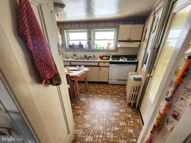 kitchen with sink, radiator heating unit, cream cabinets, and white range oven