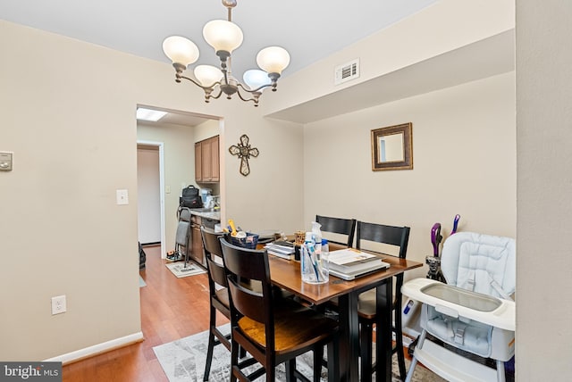 dining area with an inviting chandelier and light hardwood / wood-style flooring