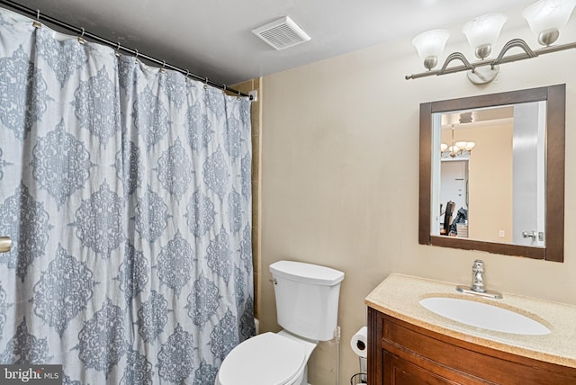 bathroom featuring vanity, an inviting chandelier, toilet, and walk in shower