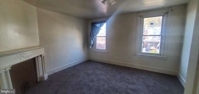 additional living space with dark colored carpet and plenty of natural light