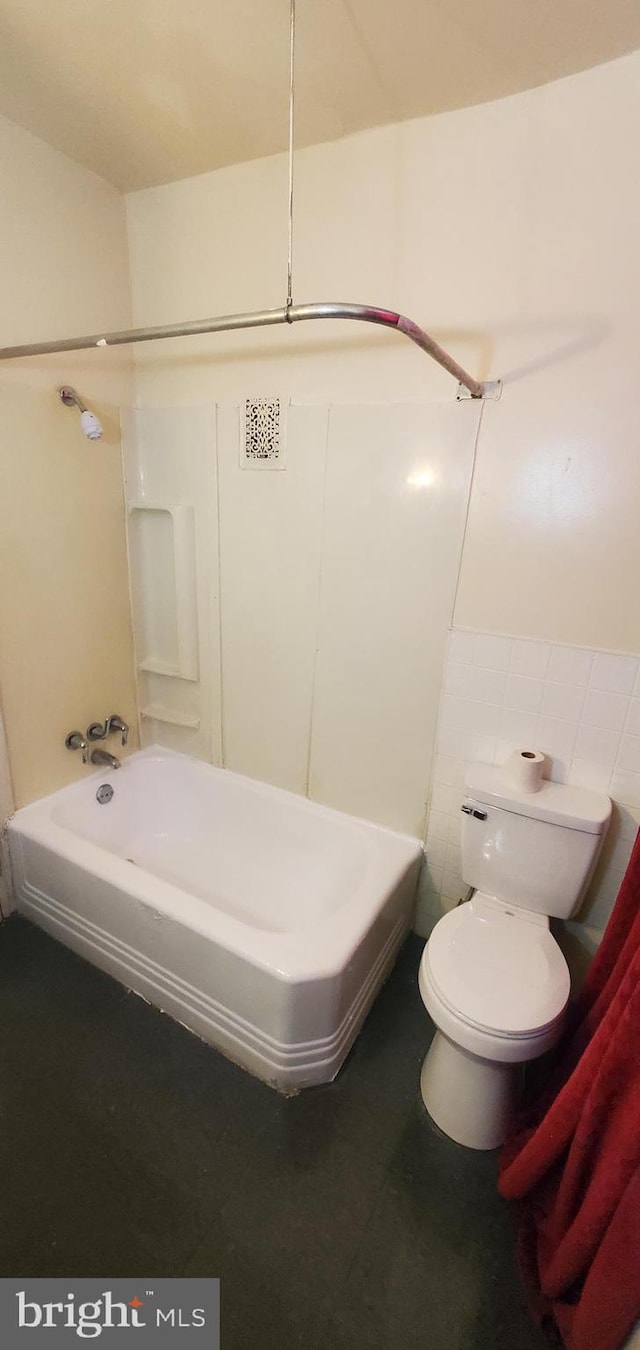 bathroom with toilet, tile walls, and shower / tub combination