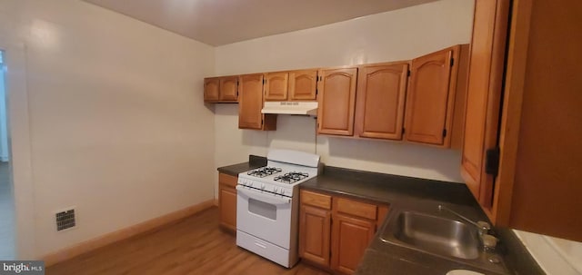 kitchen with white gas stove, sink, and light wood-type flooring