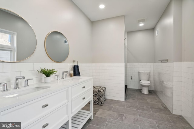 bathroom featuring toilet, vanity, and tile walls