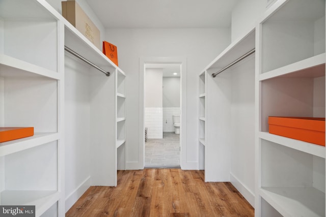 walk in closet with light hardwood / wood-style floors