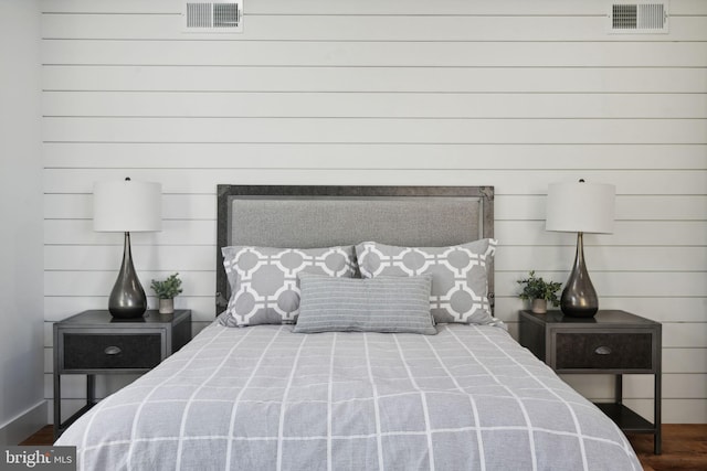 bedroom with dark hardwood / wood-style flooring and wooden walls